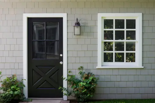 A black door and window on the side of a house.